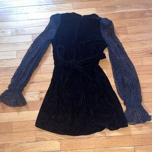 A suede black mini dress with flared lace sleeves and tie in back.